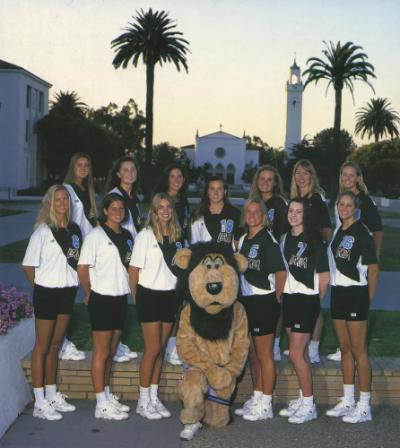 Iggy posing with athletes in Alumni Mall with Sacred Heart Chapel in the distance